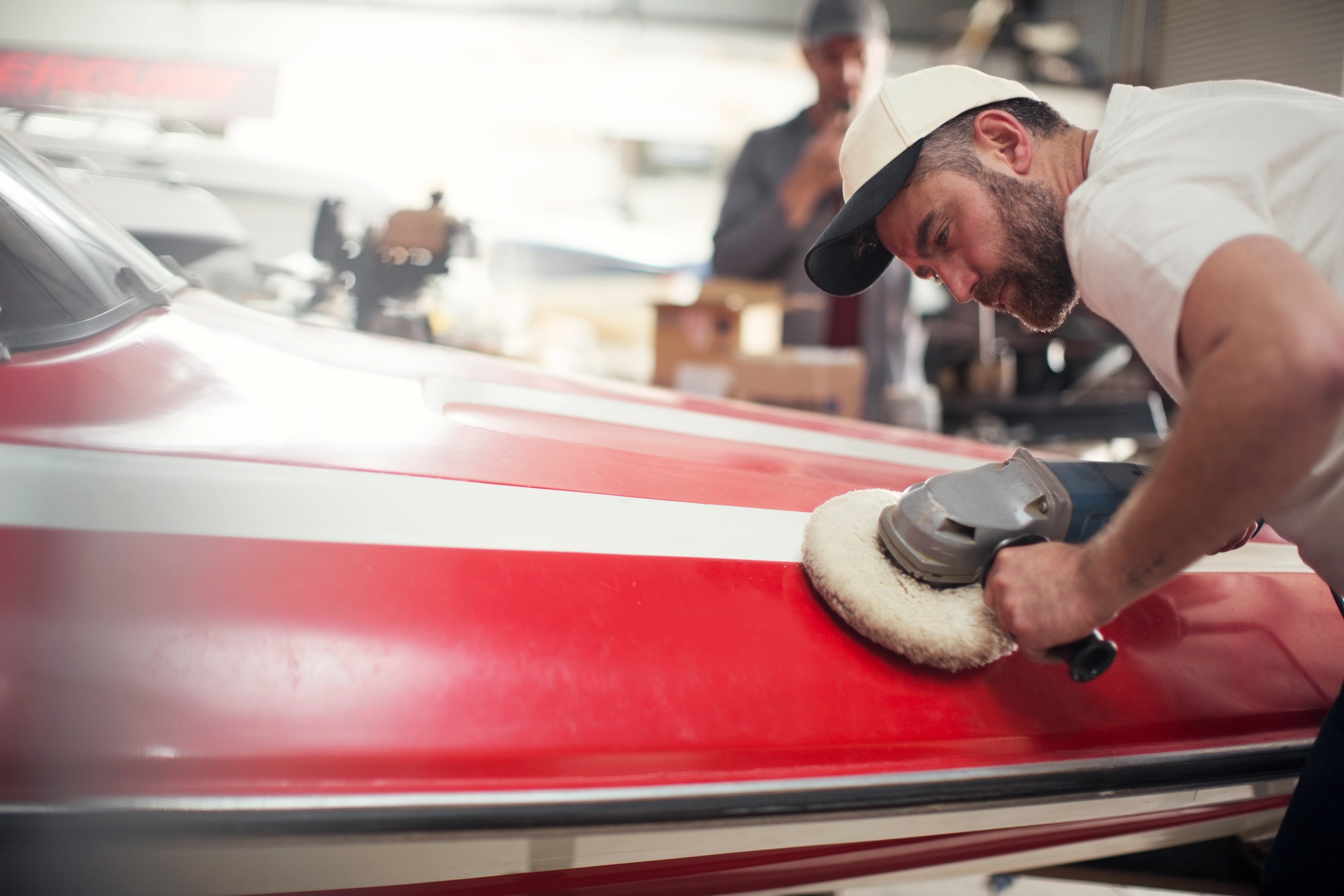 Man polishing boat in repair workshop